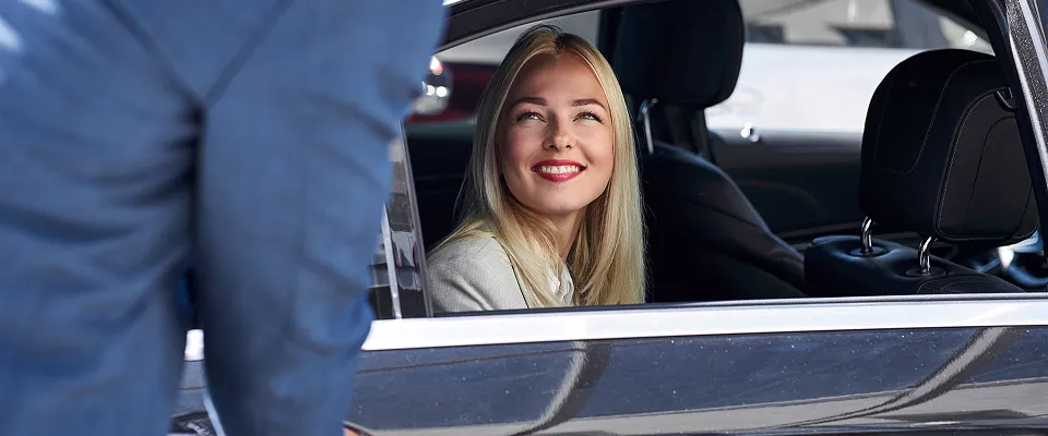 Two women smiling, as one enters a taxi